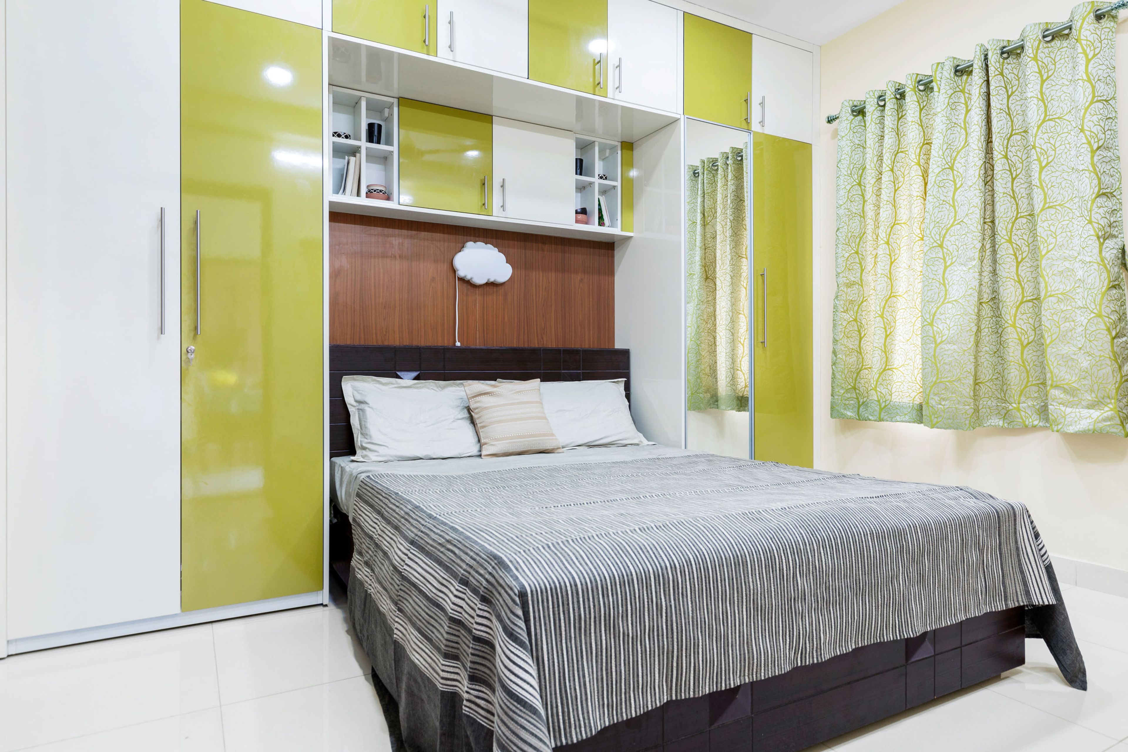 Master bedroom with mustard-yellow and white wardrobe and loft storage - Livspace