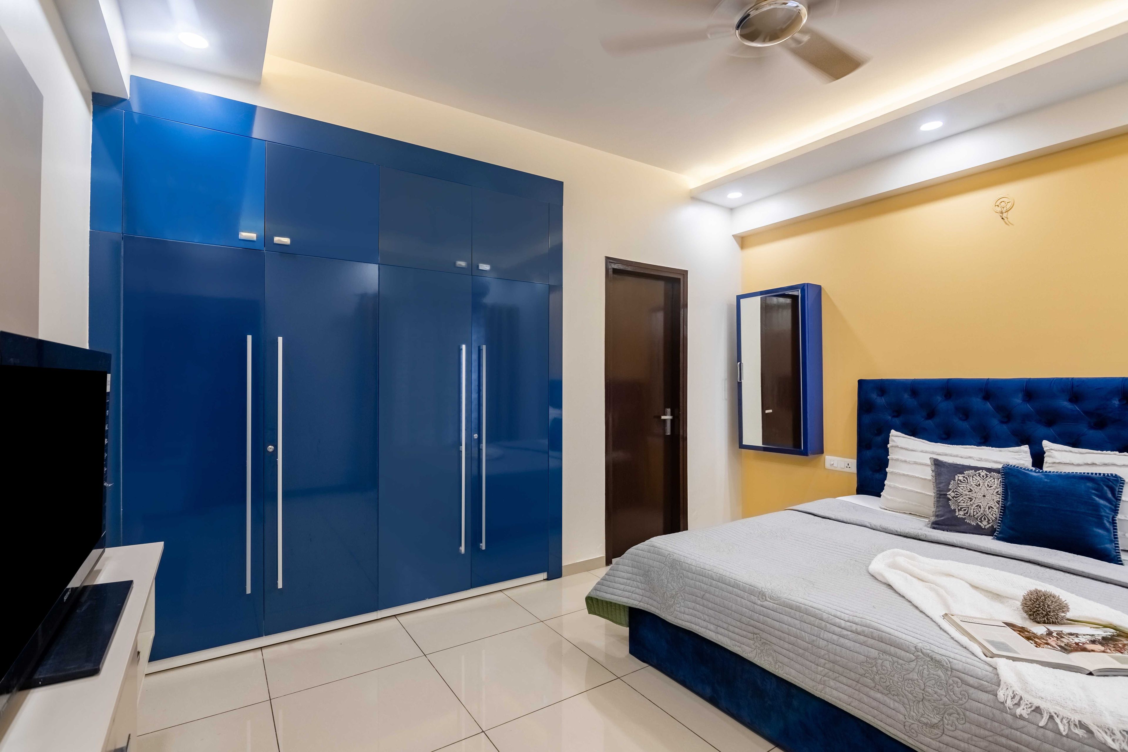 Modern Bedroom Design With A Fabric Cushioned Bed And A Beige TV Unit