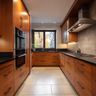 U-Shaped warm wood kitchen with black countertops, glass cabinet inserts, and modern appliances