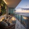 Balcony with marble flooring, firepit, glass railing, and a lush green wall