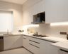 White U-Shaped kitchen with handleless cabinetry, under-cabinet lighting, and integrated modern appliances