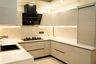 Glossy beige and white U-Shaped kitchen with roller shutter storage and black chimney centerpiece