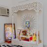 Pooja room with sunburst wall design and vibrant deity frames arranged neatly