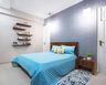 12x9 Ft Blue Guest Bedroom Design With Wooden Headboard And Wall-Mounted Shelves - Livspace