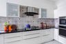 White L-shaped kitchen design with multicoloured dado tiles - Livspace