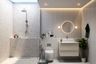 Minimal Glam Bathroom Design With White Vanity Unit, Round Mirror, Glass Partition, Grey Multicoloured Wet Area Wall Tiles And Grey Wall Panels For The Dry Area - Livspace
