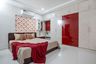 Red And Beige Guest Room Design With 6-Door Glossy Wardrobe, Wooden Bed, Red Side Table And Wall-Mounted Storage - Livspace