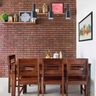 Dining Room Design With 4-Seater Wooden Dining Table And Long Bench, Wall-Mounted Wooden Shelves And Red Brick Accent Wall - Livspace